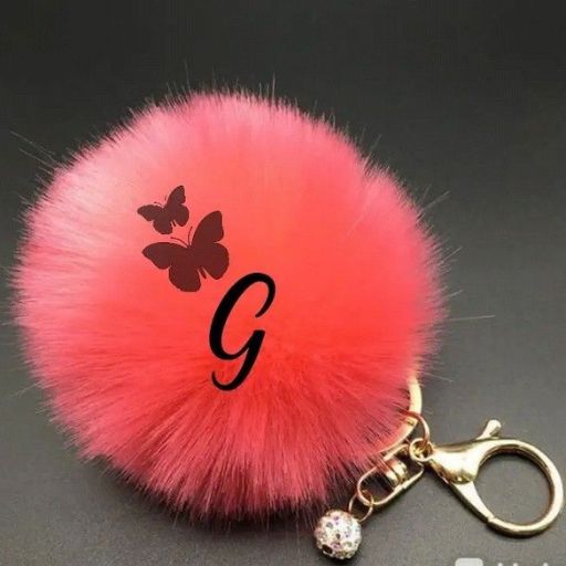 A pink fluffy keychain with a black butterfly and the letter 'G' monogrammed on it against a grey background