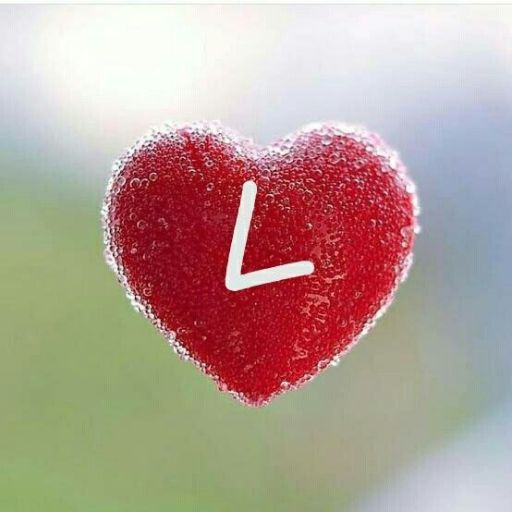 A red heart-shaped object covered in water droplets with a white clock hand pointing at 6 o'clock, against a blurred background