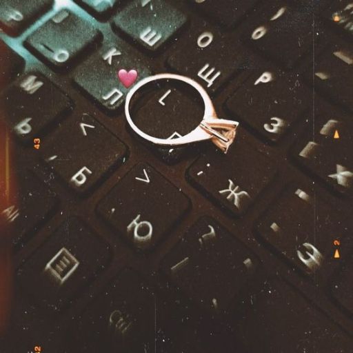 A ring with a heart on a computer keyboard with soft focus and moody lighting