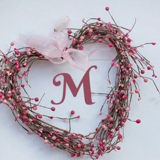 A wreath of twigs and pink buds with a pink ribbon and the letter 'M' in the center