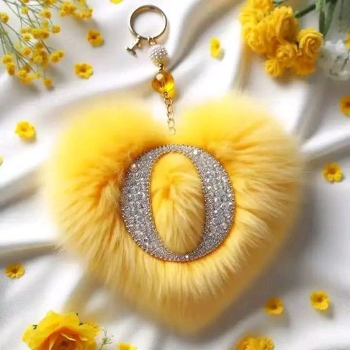 A yellow fluffy pom-pom keychain with a glittering centerpiece, surrounded by yellow flowers on a white background