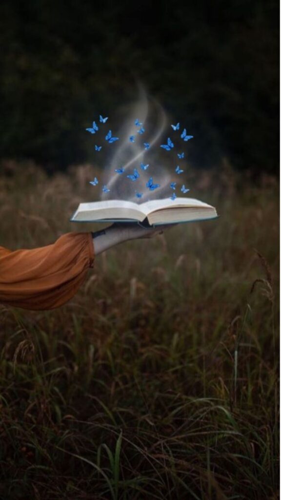 An open book held by a hand with butterflies emerging from it, set against a meadow background