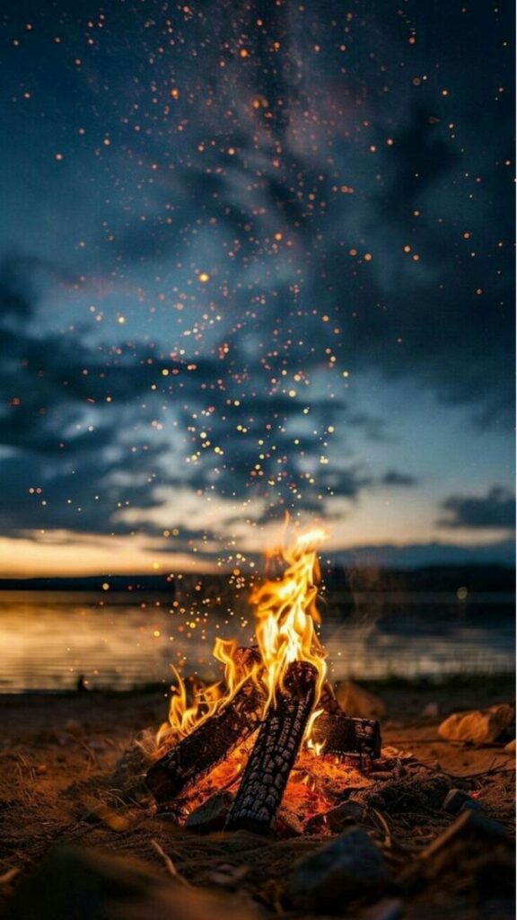 Campfire by the lake at dusk with sparkling embers rising against a twilight sky