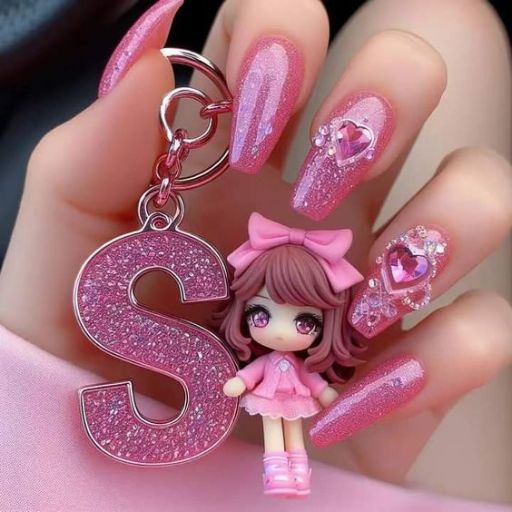 Close-up of a hand with long, glittery pink nails holding a pink keychain with a letter 'S' and a small doll attached