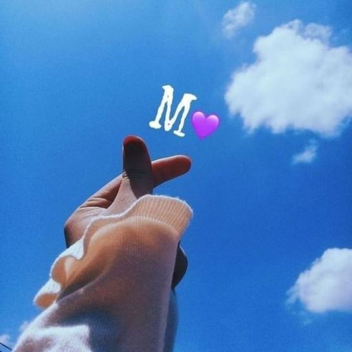 Hand reaching towards the sky with a letter 'M' and a pink heart emoji above it against a backdrop of blue sky and clouds