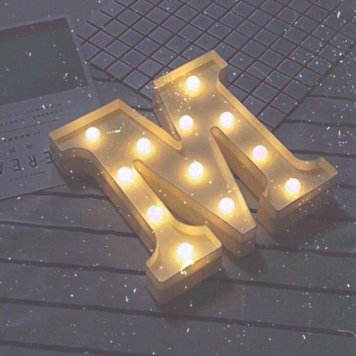 Illuminated marquee letter 'M' with warm lights on a table, creating a cozy ambience