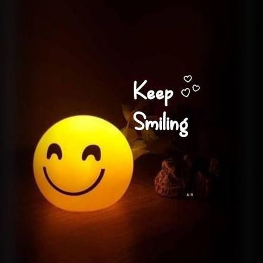 Illuminated smiley face lamp with _Keep Smiling_ text in a dark room