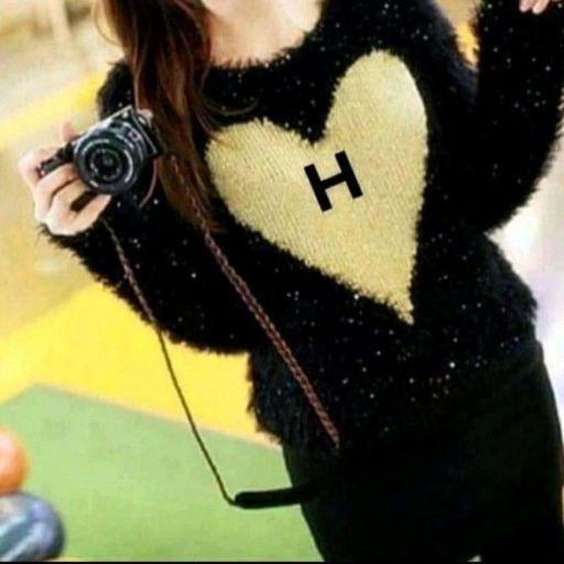 Person in a black and beige sweater with a heart design holding a camera