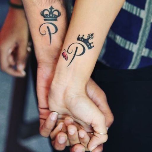 Two hands clasped together, each with a matching tattoo of a letter 'P' with a crown