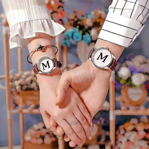 Two handTwo hands clasped wearing matching bracelets with letter 'M' on a floral backdrops clasped wearing matching bracelets with letter 'M' on a floral backdrop