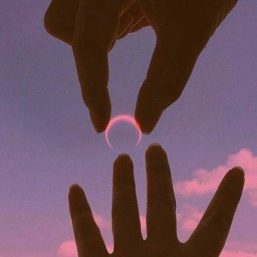 Two hands framing a small sun against a pink sky