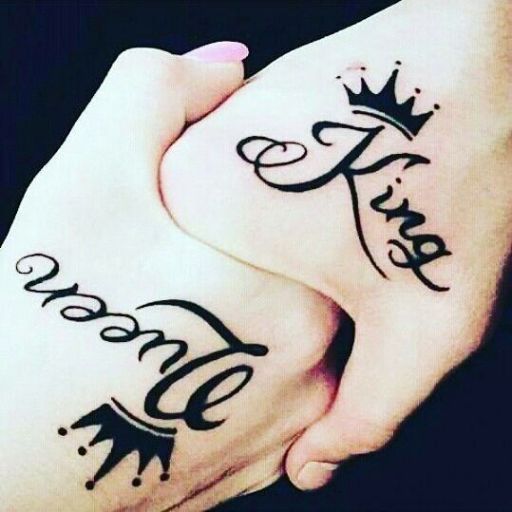 Two individuals clasp hands, showcasing tattoos that read _king_ and _queen,_ symbolizing their bond and unity