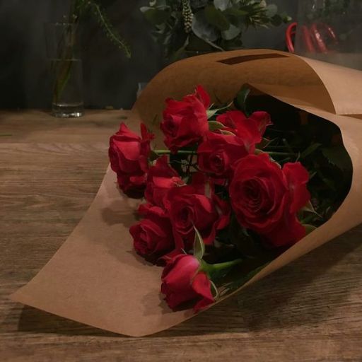 a bouquet of red roses wrapped in brown paper