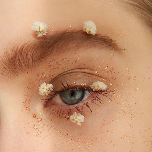 a close up of a person's eye with gold glitter on it