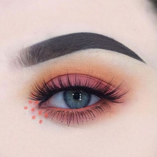 a close up of a woman's eye with red and orange makeup