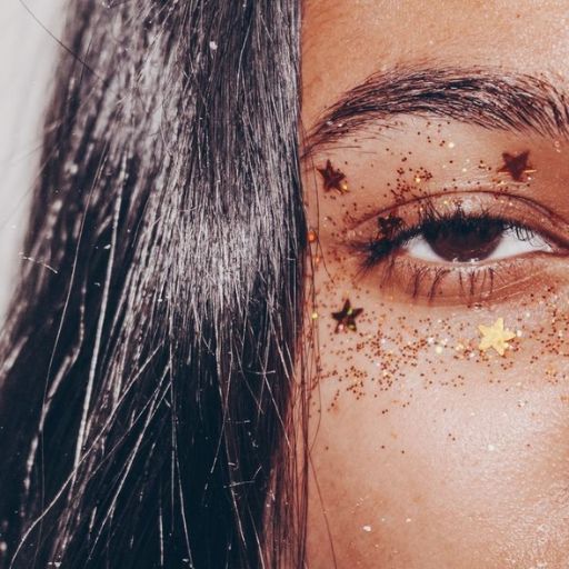 a close up of a woman's face with glitter on her eyes