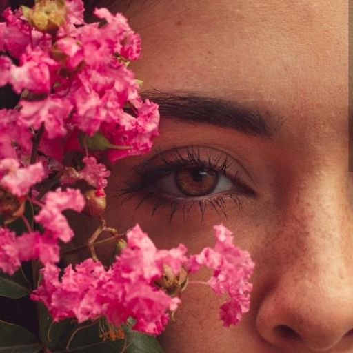 a close up of a woman's face with pink flowers in front of her