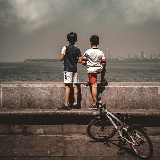 a couple of kids standing next to a bike