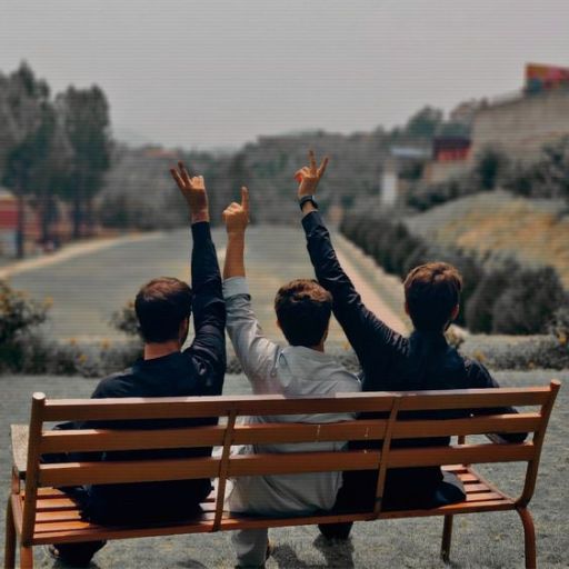 a couple of people sitting on top of a wooden bench