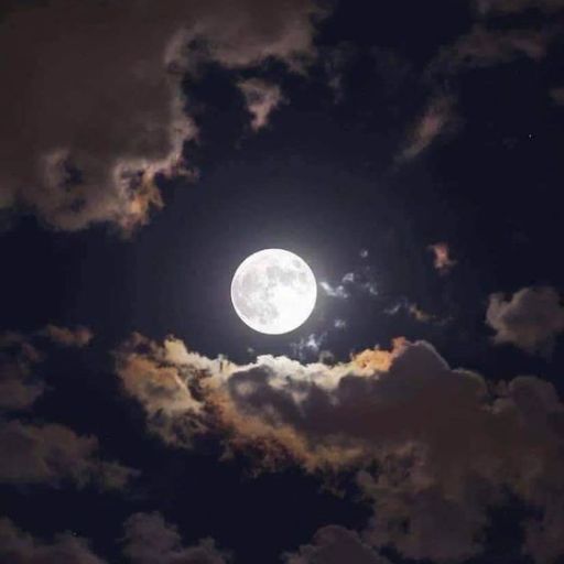 a full moon is seen through the clouds