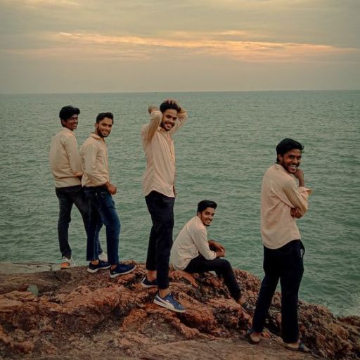 a group of men standing on top of a rocky cliff next to the ocean