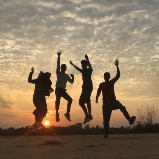 a group of people jumping in the air at sunset