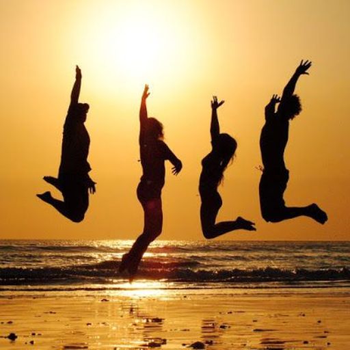 a group of people jumping into the air on a beach