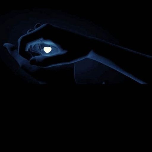 a person holding a heart shaped object in the dark