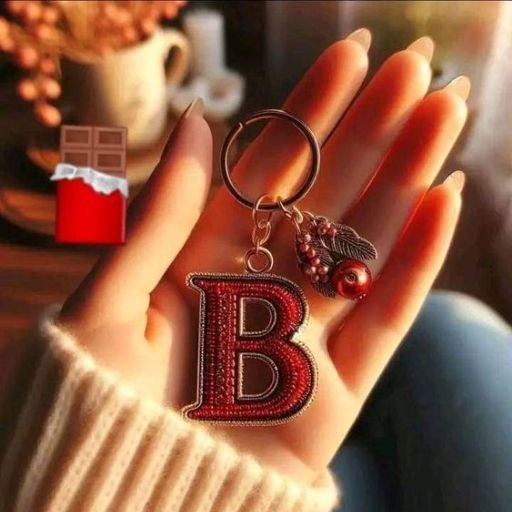 a person holding a keychain with a letter b on it