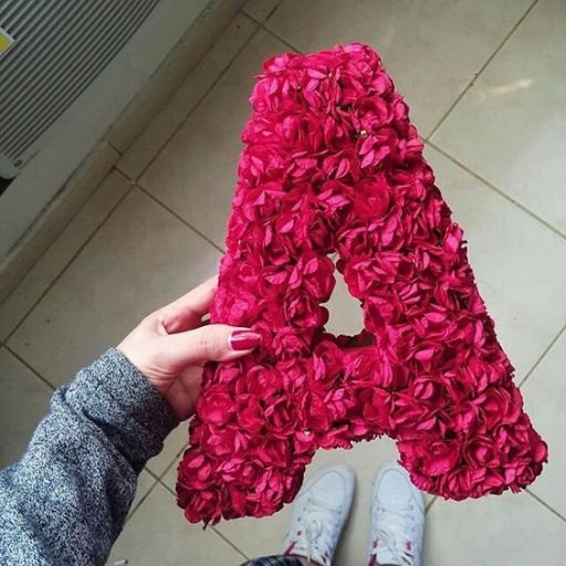 a person holding up a letter made out of flowers