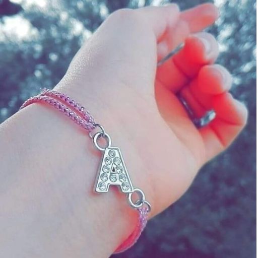 a person wearing a bracelet with a letter charm