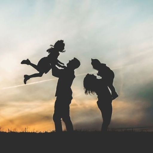 a silhouette of three people holding a child