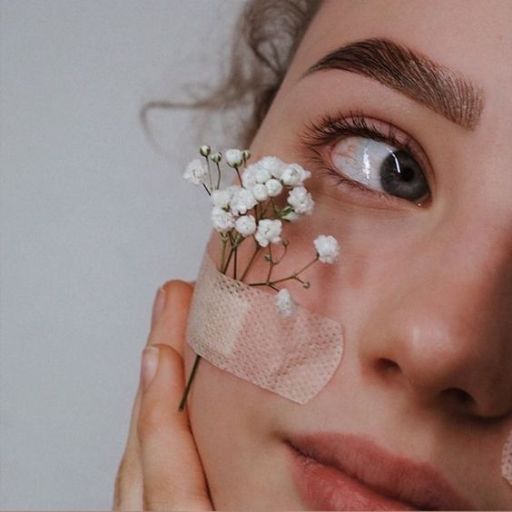 a woman holding a piece of cloth over her eye