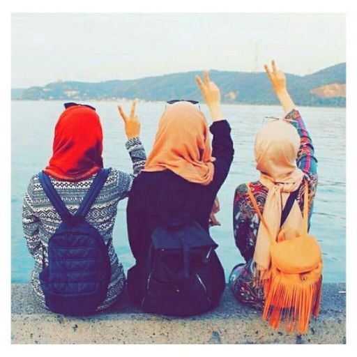 three women sitting on the shore of a body of water