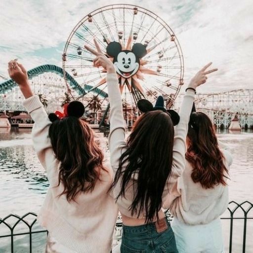 two girls are standing in front of a ferris wheel