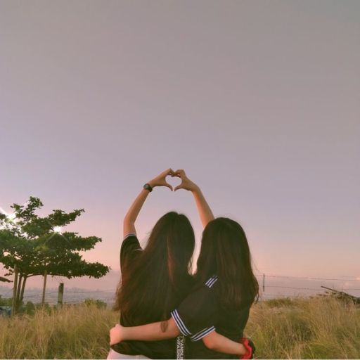 two girls making a heart shape with their hands