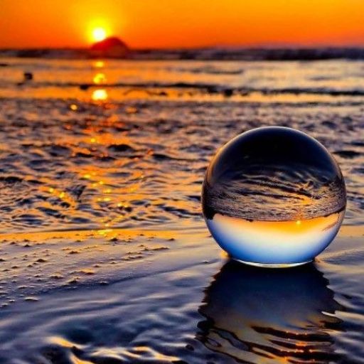 A crystal ball reflecting the sunset on a beach with glistening water