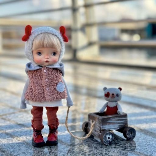 Child in a cute outfit with a toy bear in a wooden wagon, on a sunlit pavement