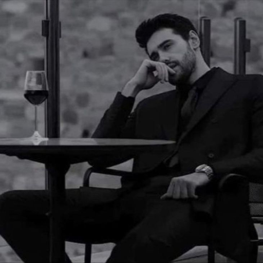 Man in suit sitting at a table with a glass of wine