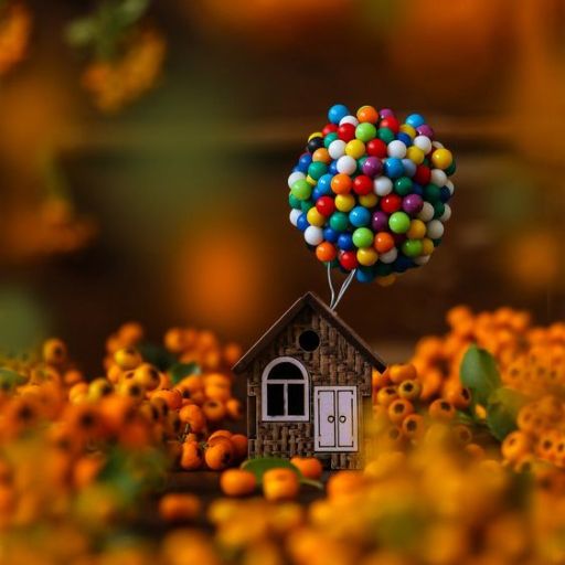 Miniature house with colorful balloons flying above an autumn-themed landscape