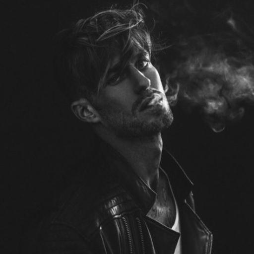 Person in a leather jacket exhaling smoke against a dark background