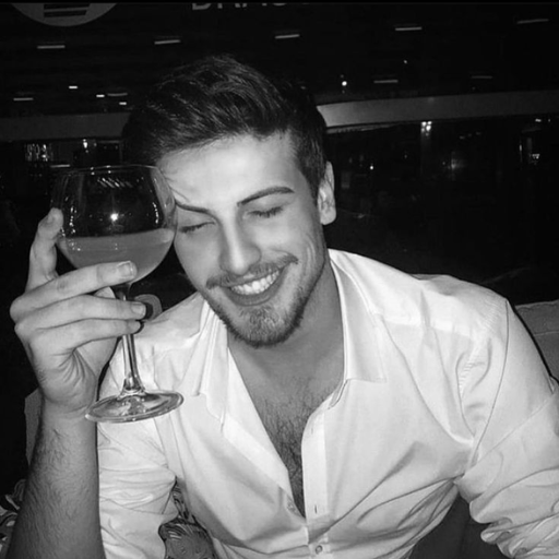 Person in a white shirt holding a glass of wine, in a dimly lit room