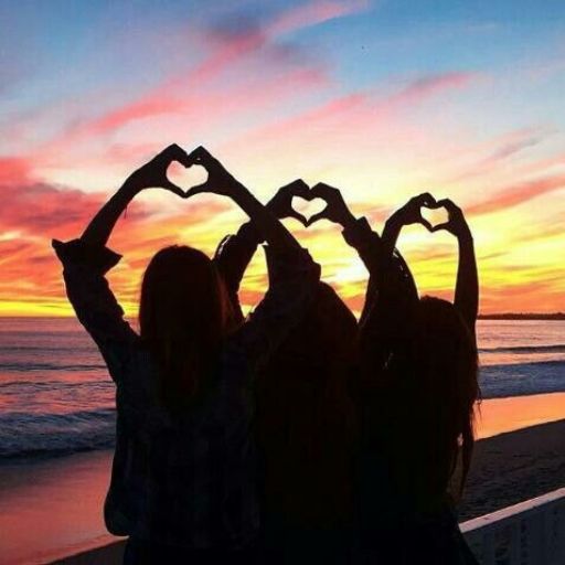 Three silhouetted people making heart shapes with their hands against a sunset beach backdrop