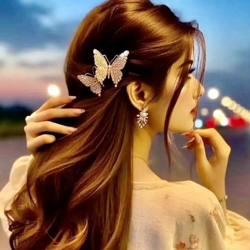 Woman with wavy hair styled with a butterfly hairpin, touching hair against a twilight backdrop