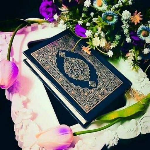 A Quran book surrounded by colorful flowers on a dark background