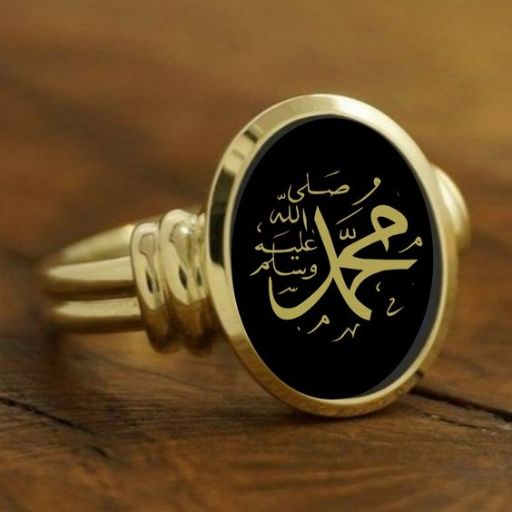 A gold ring with Arabic calligraphy on a black oval face against a wooden background