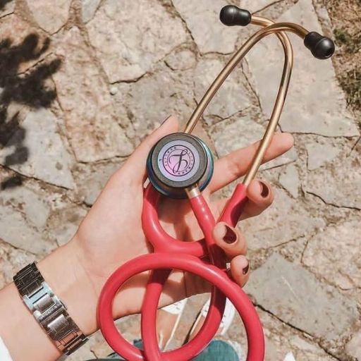 A hand holding a red stethoscope over a patterned ground