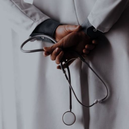 A person in a white coat holding a stethoscope against their back with crossed hands