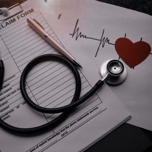 A stethoscope on insurance claim forms with a heartbeat illustration and red heart symbol