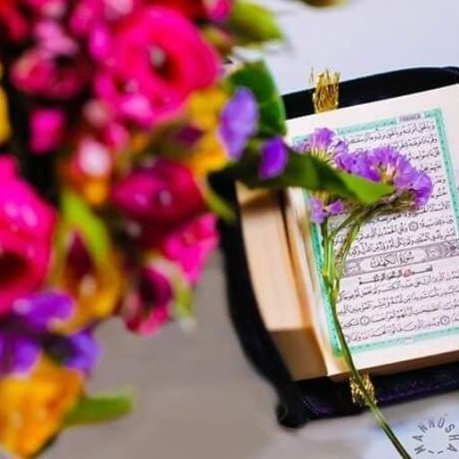 An open Quran with Arabic script next to a bouquet of vibrant flowers